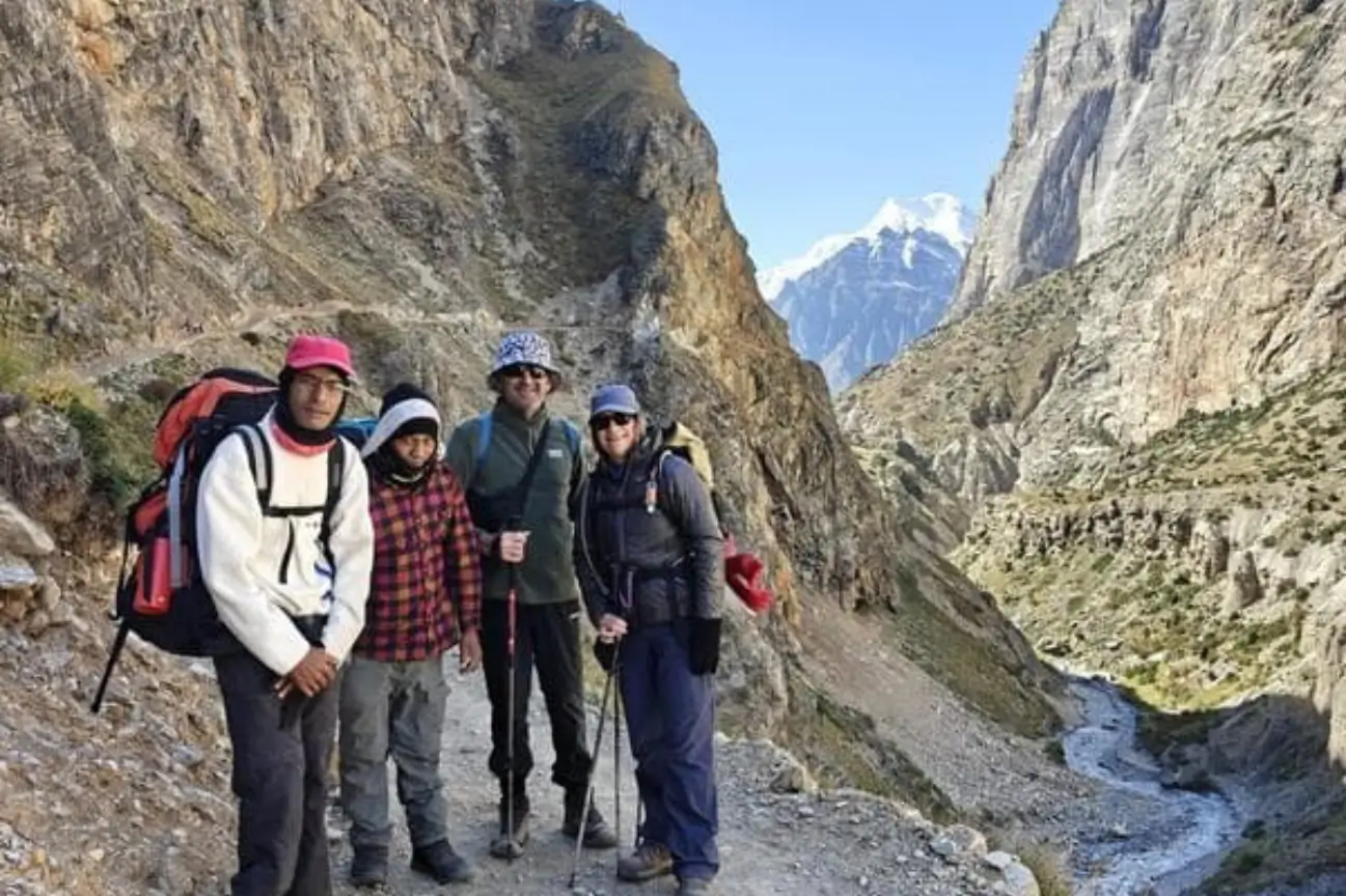 Professional trekking guides and travelers smiling together on a rugged mountain trail during the Annapurna Base Camp Trek.